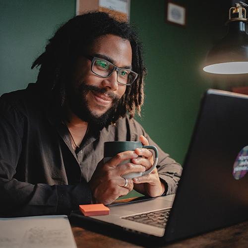 online male student working on a project on a laptop computer smiling, learn innovation