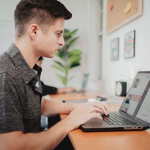 male student working on an assignment at his computer, learn innovation